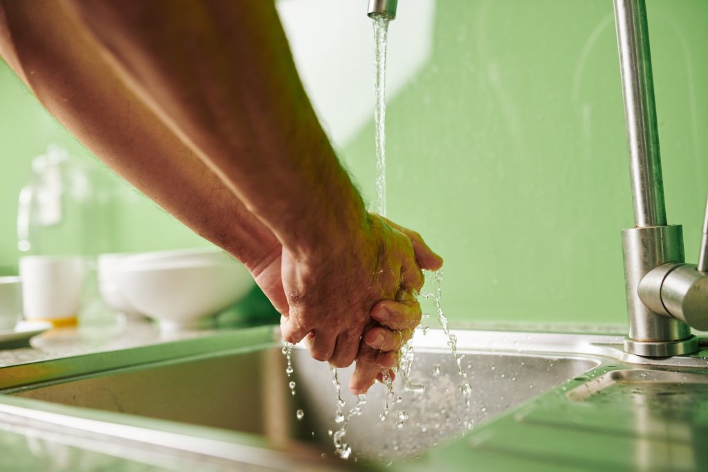 Man rinsing hands under tap water